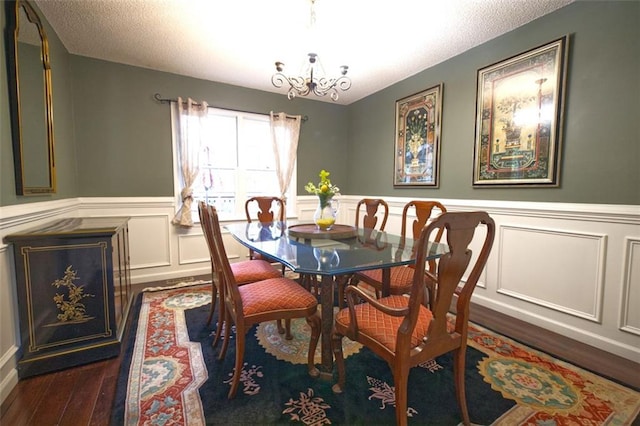 dining room with dark hardwood / wood-style flooring, a textured ceiling, and an inviting chandelier