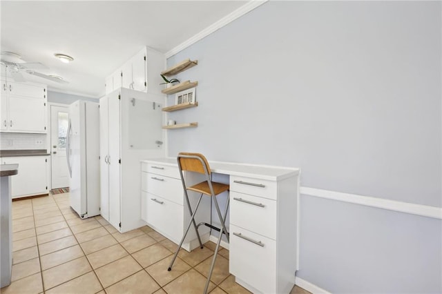 office featuring a ceiling fan, built in study area, ornamental molding, and light tile patterned floors