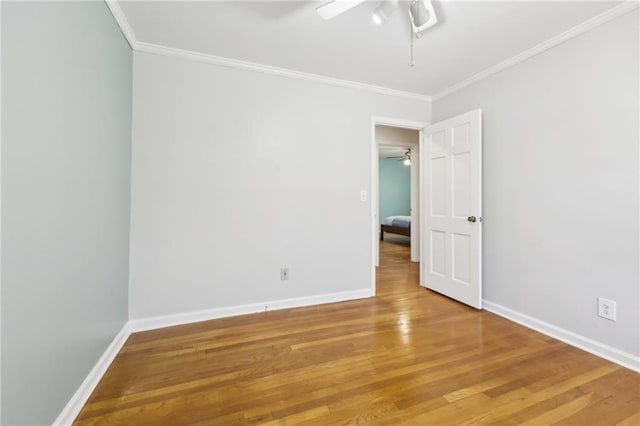 spare room featuring a ceiling fan, crown molding, light wood-style flooring, and baseboards