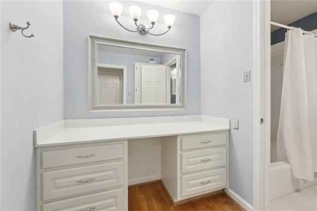 bathroom with shower / bath combo, wood finished floors, vanity, and baseboards