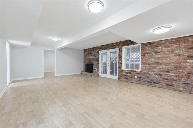 basement featuring brick wall, a fireplace, wood finished floors, and baseboards