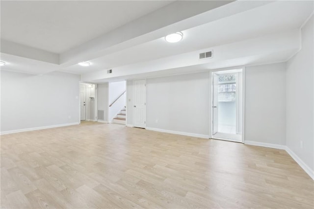 basement with light wood-type flooring, baseboards, stairs, and visible vents