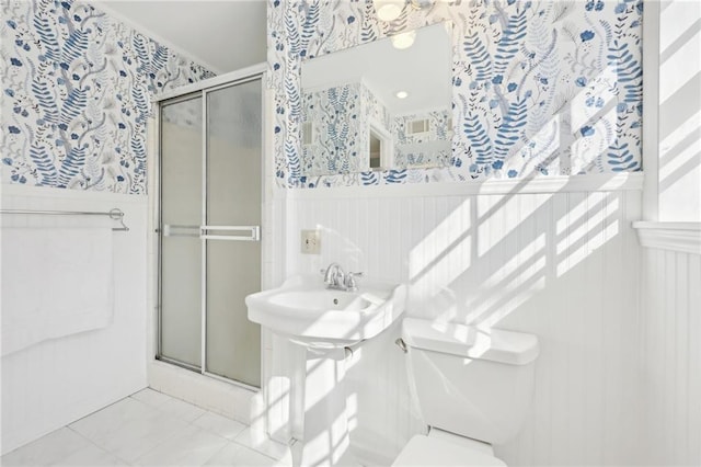 bathroom with toilet, a wainscoted wall, and a stall shower