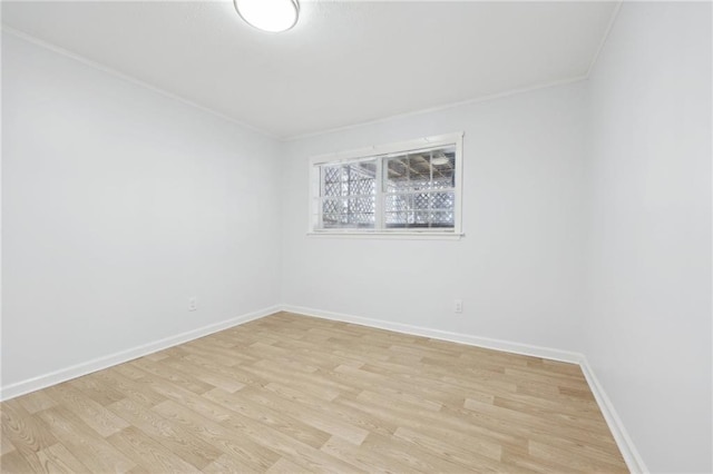 spare room featuring baseboards, ornamental molding, and light wood-style floors