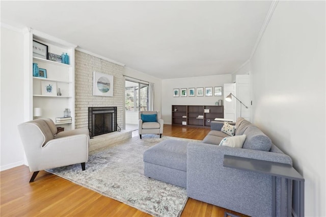 living area featuring baseboards, a fireplace, wood finished floors, and crown molding