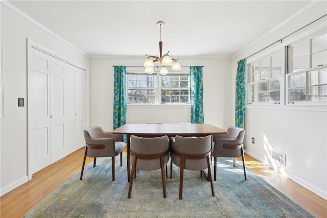 dining space featuring ornamental molding, a notable chandelier, baseboards, and wood finished floors