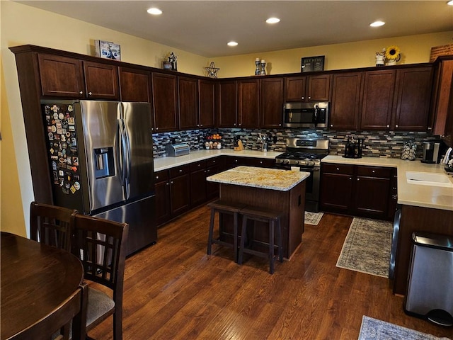 kitchen with sink, a kitchen breakfast bar, dark hardwood / wood-style flooring, a center island, and stainless steel appliances