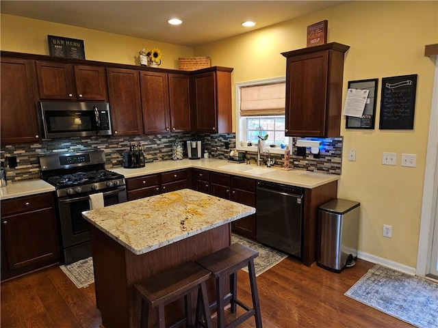 kitchen featuring appliances with stainless steel finishes, dark hardwood / wood-style flooring, sink, and a kitchen island