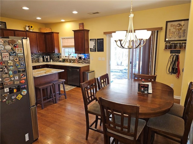 dining space featuring an inviting chandelier, sink, and dark wood-type flooring