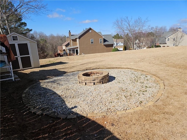 view of yard featuring a storage shed and an outdoor fire pit