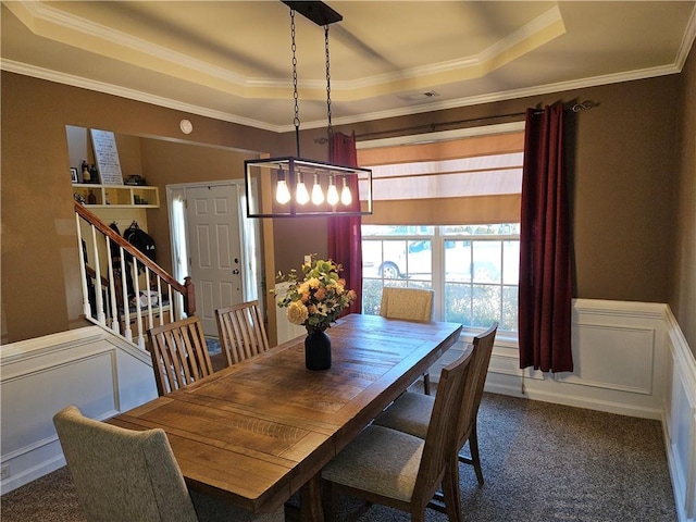 dining area featuring ornamental molding, a raised ceiling, and dark colored carpet