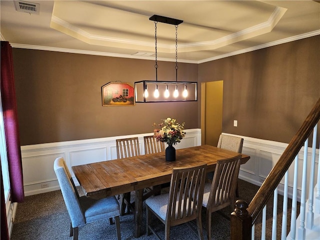 dining space featuring crown molding, a raised ceiling, and dark colored carpet