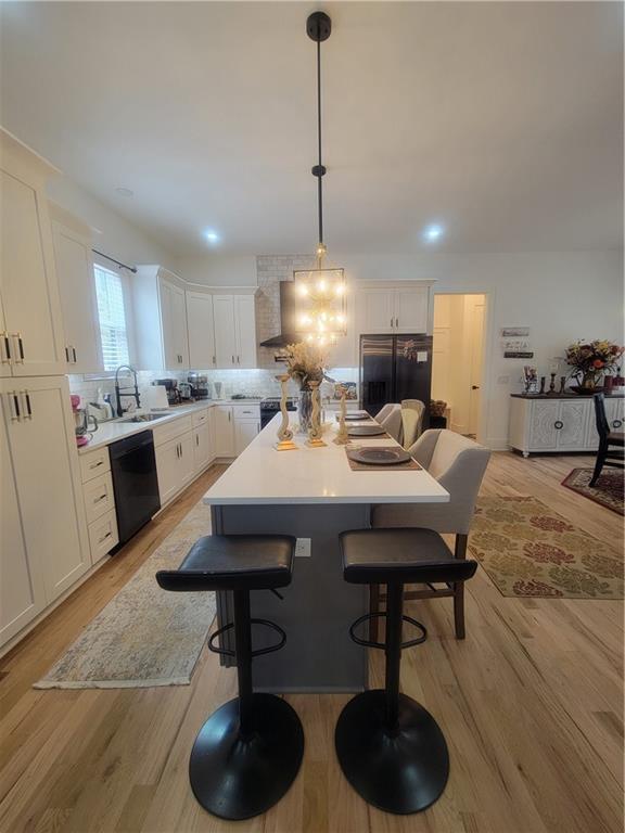 kitchen with pendant lighting, a center island, stainless steel built in fridge, light hardwood / wood-style flooring, and black dishwasher