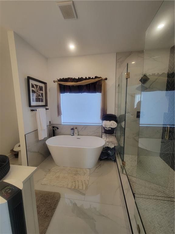 bathroom with shower with separate bathtub and tile walls