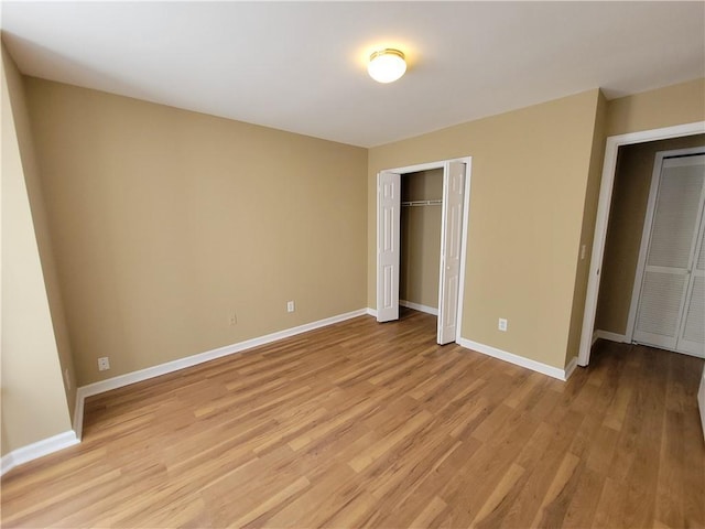 unfurnished bedroom featuring light wood-type flooring, baseboards, and a closet