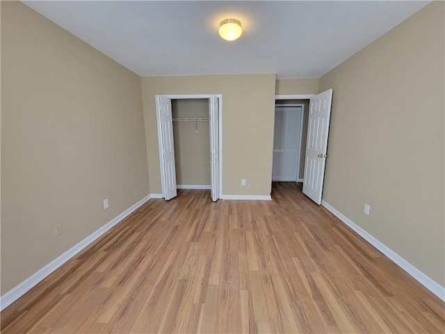 unfurnished bedroom with light wood-style flooring, baseboards, and a closet