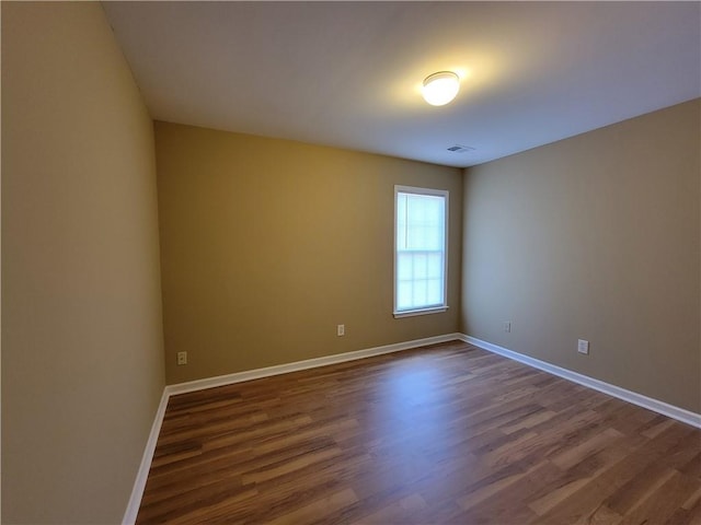 empty room featuring dark wood-style flooring and baseboards