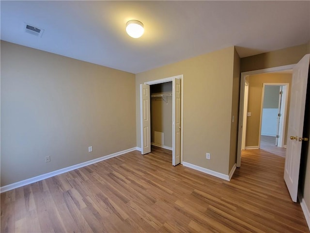 unfurnished bedroom featuring light wood-type flooring, baseboards, and a closet