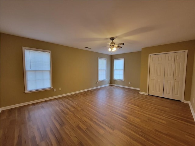 unfurnished bedroom with wood finished floors, baseboards, a ceiling fan, and a closet