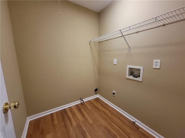 clothes washing area featuring hookup for a gas dryer, washer hookup, hookup for an electric dryer, wood finished floors, and baseboards