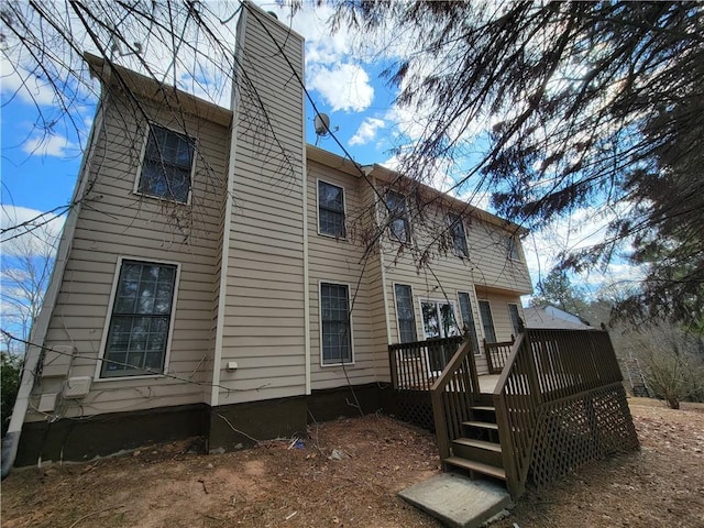 back of property with a chimney and a deck