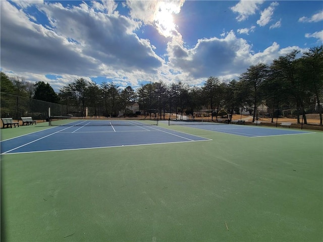 view of tennis court with community basketball court and fence