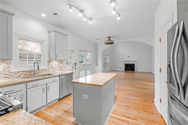4120 Lakeside Blvd, Monroe, GA 30655 - kitchen with stainless steel appliances, a sink, arched walkways, a center island, and a fireplace