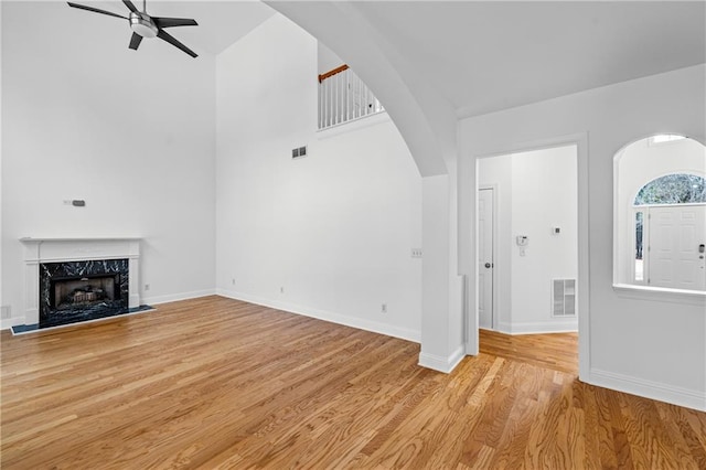 4120 Lakeside Blvd, Monroe, GA 30655 - unfurnished living room featuring arched walkways, ceiling fan, light wood-type flooring, baseboards, and a high ceiling