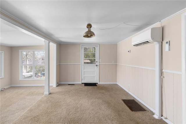 spare room featuring crown molding, a wall mounted AC, wainscoting, visible vents, and carpet