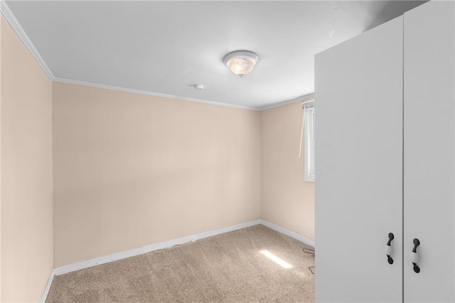 empty room with carpet flooring, crown molding, and baseboards
