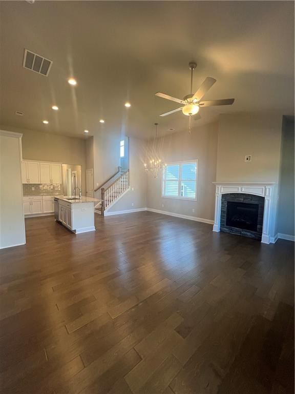 unfurnished living room featuring sink, ceiling fan with notable chandelier, and dark hardwood / wood-style floors