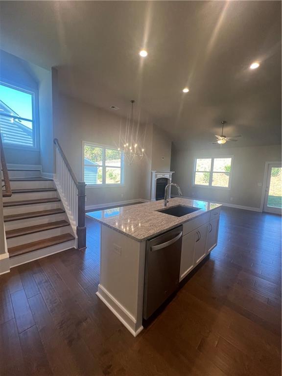 kitchen with white cabinetry, dishwasher, sink, hanging light fixtures, and a center island with sink