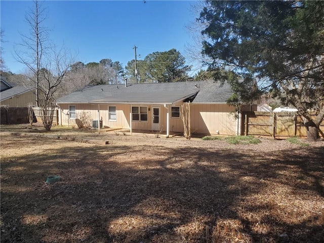 rear view of house featuring a gate, central AC, and fence