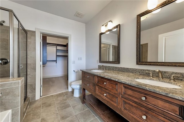 bathroom featuring vanity, toilet, a shower with shower door, and tile patterned flooring