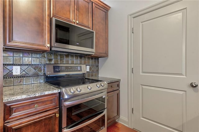 kitchen featuring light stone countertops, appliances with stainless steel finishes, and decorative backsplash