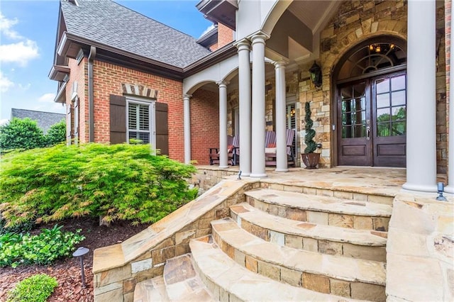 31 Brownson Ct, Acworth, GA 30101 - view of exterior entry featuring a shingled roof, a porch, stone siding, and brick siding