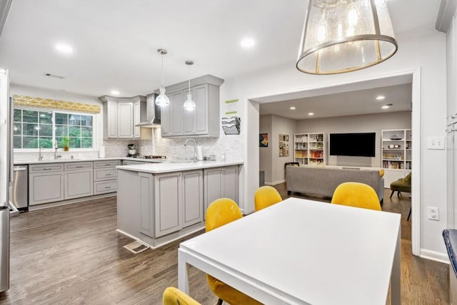 1315 Merry Ln NE, Atlanta, GA 30329 - kitchen with wall chimney range hood, gray cabinets, dark wood-style floors, tasteful backsplash, and a peninsula