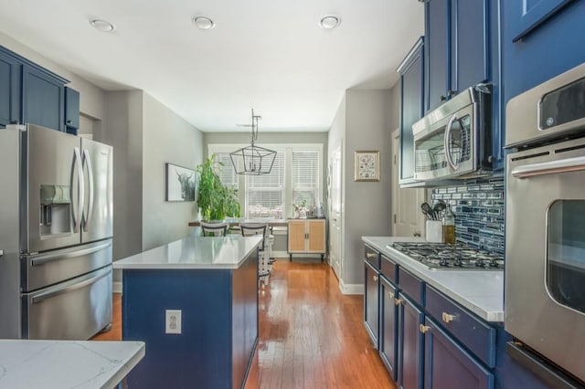 2075 Old Georgian Ter NW, Atlanta, GA 30318 - kitchen featuring stainless steel appliances, blue cabinetry, wood finished floors, backsplash, and a center island