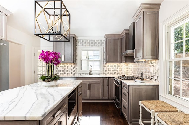 kitchen with built in microwave, a sink, high end stainless steel range, light stone countertops, and pendant lighting