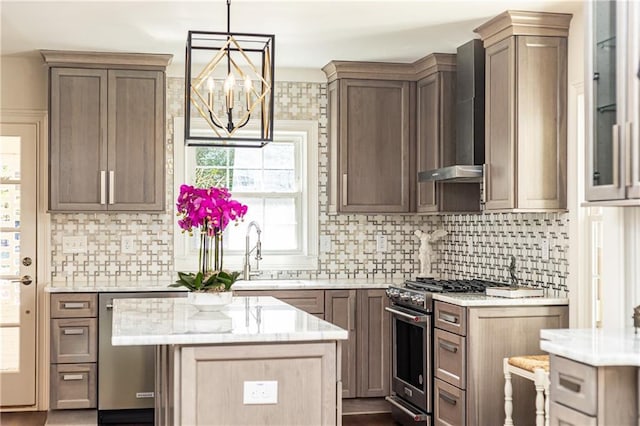 kitchen featuring a center island, appliances with stainless steel finishes, glass insert cabinets, a sink, and wall chimney exhaust hood