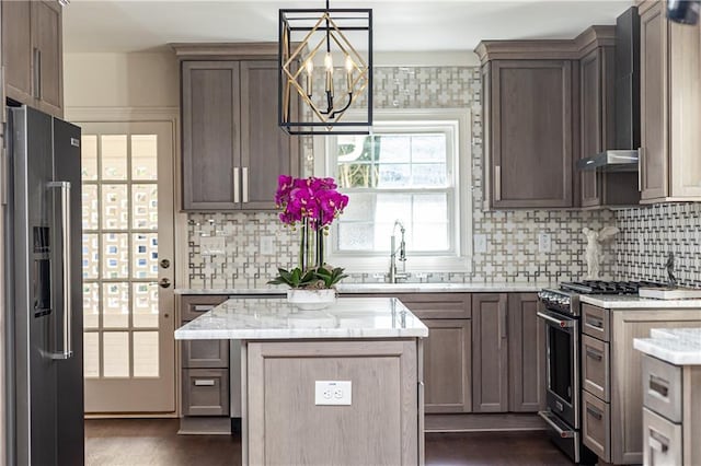 kitchen featuring premium appliances, a kitchen island, decorative light fixtures, light stone countertops, and a sink