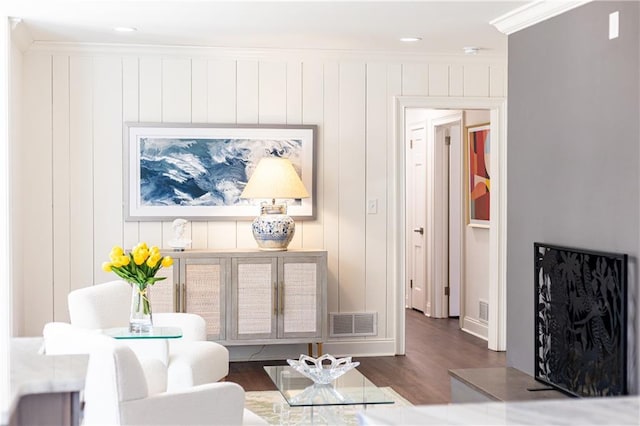 living area with ornamental molding, dark wood finished floors, and visible vents