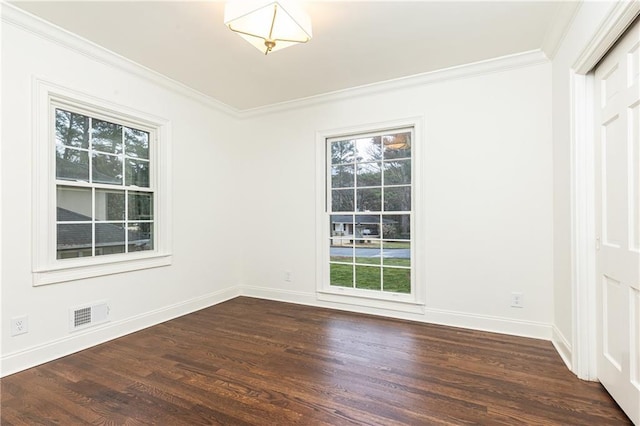 spare room featuring dark wood-style floors, visible vents, ornamental molding, and baseboards