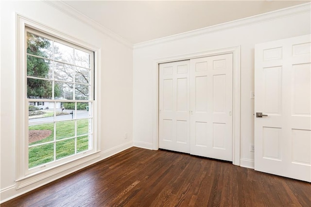 unfurnished bedroom featuring baseboards, a closet, ornamental molding, and dark wood-type flooring