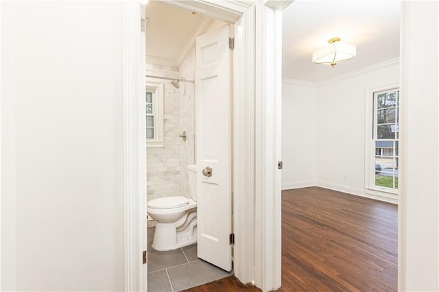 bathroom with baseboards, crown molding, toilet, and wood finished floors