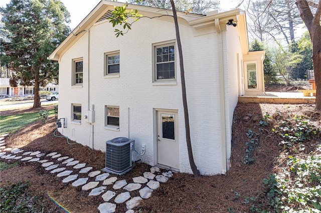 view of side of home featuring cooling unit and brick siding