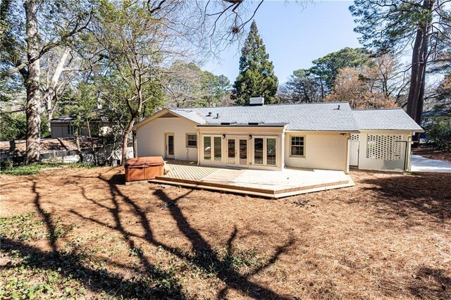 rear view of house featuring a deck, a hot tub, and stucco siding