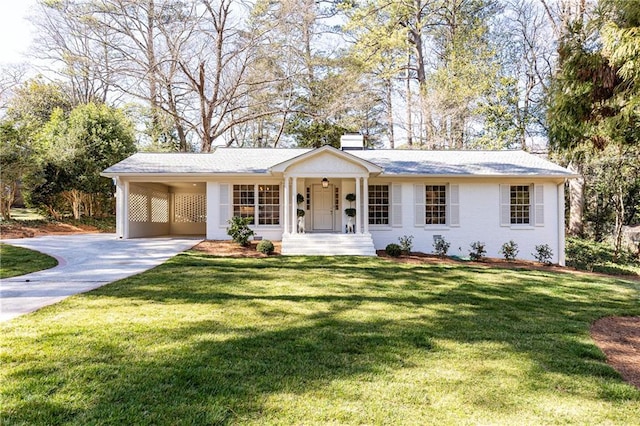 ranch-style house featuring a carport, a front lawn, a chimney, and driveway