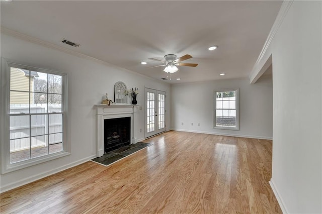 unfurnished living room featuring crown molding, a tile fireplace, ceiling fan, wood-type flooring, and french doors