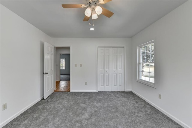 unfurnished bedroom with ceiling fan, dark carpet, and a closet